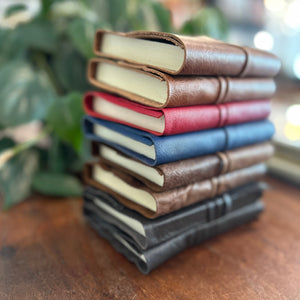A small pile of leather wrap journals in a variety of colours