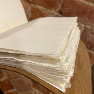 Open rustic wrap journal showing hand torn, handmade paper pages against a brick background