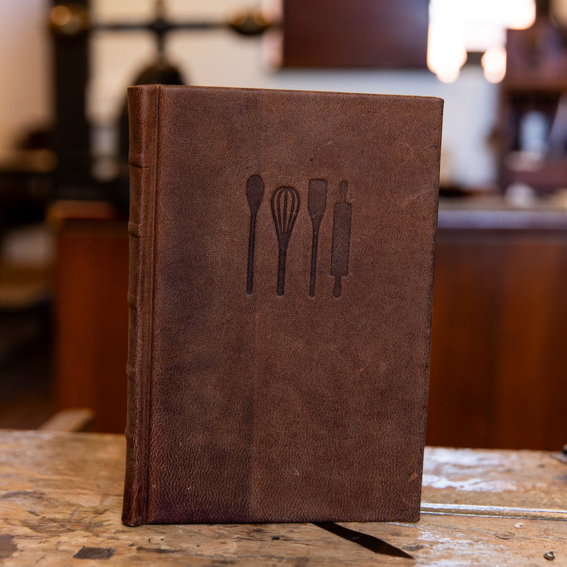 Handcrafted leather cook's journal embossed with kitchen utensil icons, made by SB Libris in Bendigo.