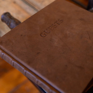 Close-up of the aged goatskin leather cover with “GUESTS” blind embossed, highlighting the soft texture and natural markings of the leather.