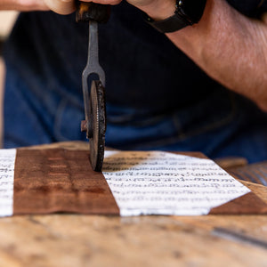 Close-up of traditional hand tooling on an SB Libris half leather journal featuring aged goatskin spine and vintage sheet music cover.