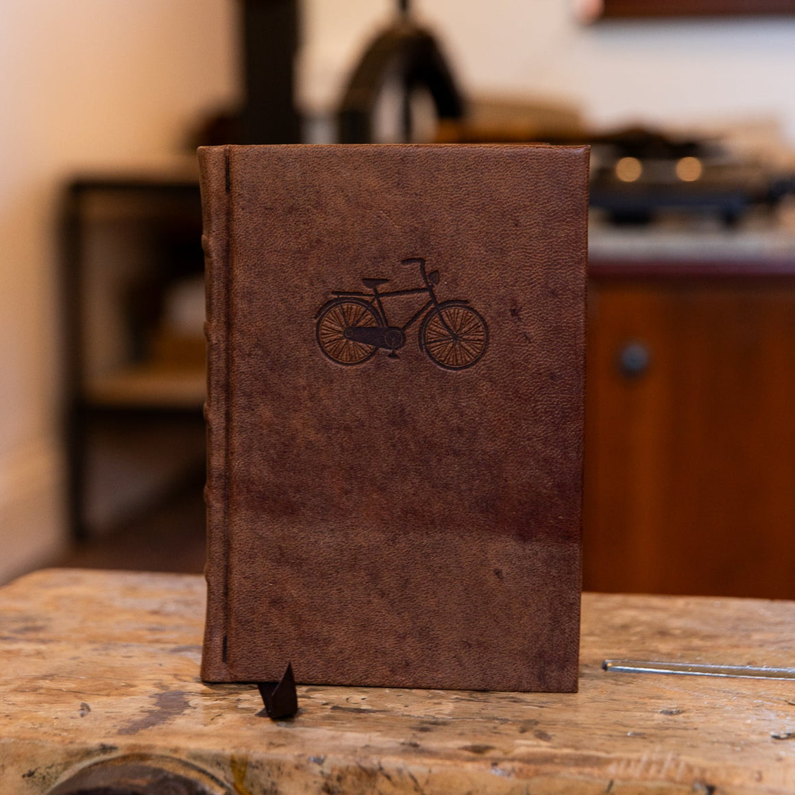Front view of the small 'On Ya Bike' journal by SB Libris, bound in brown leather with an embossed classic bicycle design.